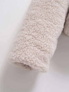 Close-up detail of plush beige sherpa fleece texture on a stylish winter jacket sleeve
