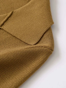 Detail of mustard yellow knit sweater showing fine texture and neckline stitching