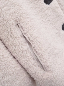 Detail of warm beige sherpa fleece texture with horn button and satin-lined pocket