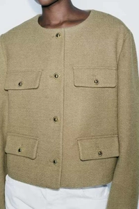 Detail view of olive green tweed jacket with vintage metal buttons and four pocket design