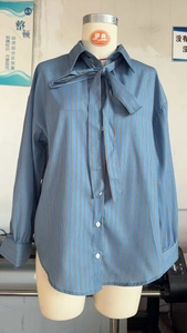 Detail of blue and brown striped shirt showing the tie-neck bow and button closure