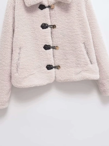 Close-up of cream faux shearling jacket featuring vintage horn buckles and leather straps
