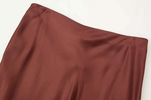 Close-up of wine red satin midi skirt showing silky texture and seamless waist detail