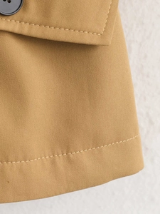Detailansicht eines khakifarbenen Trenchcoats aus Twill-Baumwolle mit schwarzem Knopf