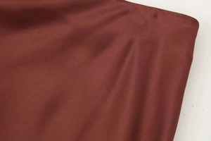 Close-up of deep red satin fabric showing smooth texture and high-quality edge stitching