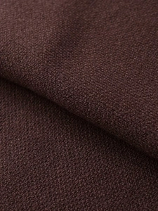 Macro shot of dark coffee bouclé knit fabric texture with soft granular boucle loop finish