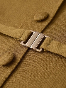 Macro shot of mustard yellow knit fabric detailing with polished gold metal buckle