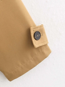 Detailaufnahme der verstellbaren Manschette mit Marmorknopf an einem camelfarbenen Trenchcoat
