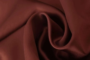 Close-up of deep burgundy satin fabric texture showing smooth drape and glossy finish