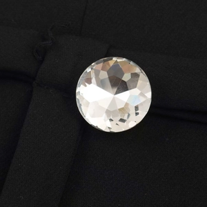 Dettaglio macro del bottone in cristallo sfaccettato su tessuto nero della gonna