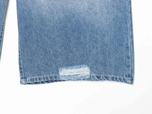 Detailed macro shot of distressed ripped design and white fiber texture on light blue denim