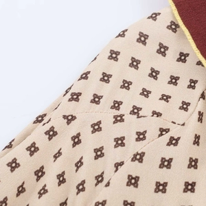 Detailed view of beige patterned fabric with geometric prints and yellow contrast stitching