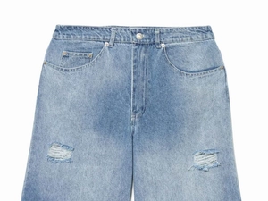 Detailed view of light blue denim fabric with distressed ripped texture on wide leg pants