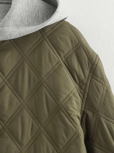 Détail de la veste matelassée olive avec capuche grise contrastée et losanges
