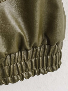 Macro view of olive green faux leather fabric texture with elastic ribbed hem detail