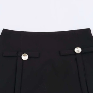 Dettaglio degli eleganti pantaloncini a gonna neri con fibbie in strass e nastri decorativi