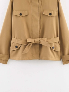 Detailaufnahme des khakifarbenen Trenchcoats mit vier Pattentaschen und Bindegürtel