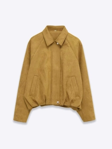 Détail de la veste en daim jaune moutarde montrant la texture et le bouton pression argenté