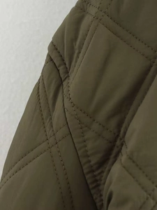 Vue macro montrant les détails du matelassage en losanges du manteau rembourré vert olive