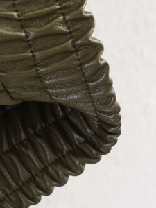 Detail of deep olive faux leather jacket featuring elasticated gathered cuffs and fine texture