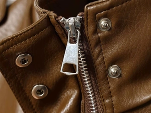 Close-up of brown faux leather texture with silver metal zipper and snap button details