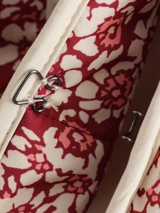 Detail of metal hook closure on floral print quilted jacket fabric with red pattern