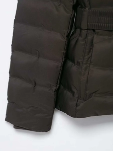 Détail d'une doudoune marron foncé avec ceinture élastique et textures de poches