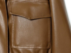 Close-up of brown textured faux leather jacket featuring a flap pocket and neat stitching