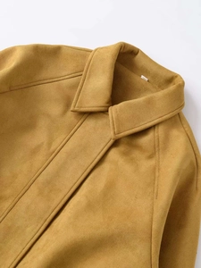 Détail d'une veste en suédine jaune moutarde avec col classique et surpiqûres élégantes