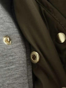 Vue macro du tissu matelassé vert olive avec bouton-pression doré et double couture