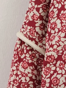 Close-up of red floral quilted jacket featuring precise beige piping and fine stitching