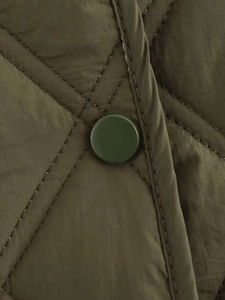 Détail d'une veste matelassée vert olive avec surpiqûres en losange et bouton-pression