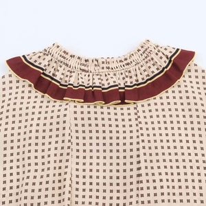 Detail of printed dress with geometric stars and pleated burgundy striped collar