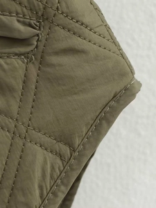 Vue macro de la veste matelassée vert olive avec motifs de coutures en losanges