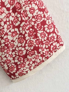 Detailed macro view of red floral quilted fabric with beige piped edge finish