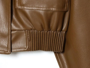 Detailed macro view of brown PU leather jacket hem with elastic pleats and flap pocket