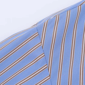 Close-up of fine shoulder stitching and striped cotton fabric on a blue and brown shirt