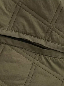 Gros plan sur le tissu matelassé vert olive avec motifs en losanges et fines coutures