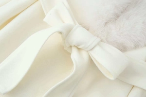Detail of cream wool coat featuring a plush faux fur collar and an elegant waist tie belt