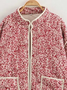 Detail view of red floral quilted jacket with standing collar and white piping detail