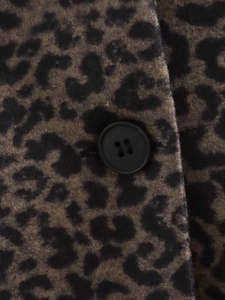 Detailed close-up of leopard print wool coat texture with a black resin button fastener