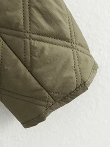 Détail macro du tissu matelassé en losanges et coutures de la veste à capuche olive