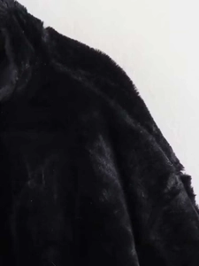 Close-up of black faux fur texture with long fluffy hair and soft glossy finish