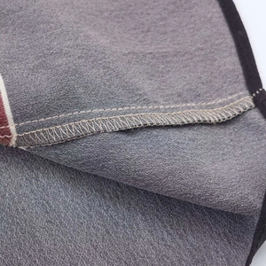 Close-up of fabric edge showing precise lockstitch sewing and gray woven texture