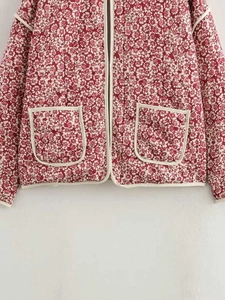 Close-up of floral quilted jacket featuring contrasting white piping and two front pockets