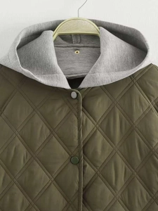 Détail d'une veste matelassée vert olive avec capuche gris clair et boutons-pression
