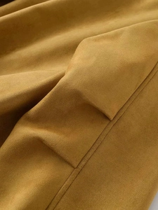 Détail d'une veste en daim camel montrant les coutures et la texture du tissu