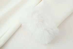 Detailed close-up of premium white faux fur trim on a minimalist long wool coat sleeve