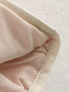 Close-up of contrast binding and precise quilting craftsmanship on a printed cotton jacket