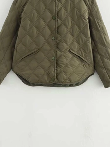 Détail d'une veste matelassée vert armée avec surpiqûres en losange et boutons pression
